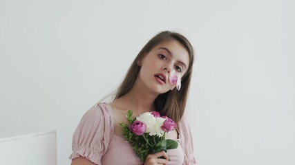 Professional young woman model with flowers looking and posing at camera