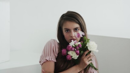 Professional young woman model with flowers looking and posing at camera