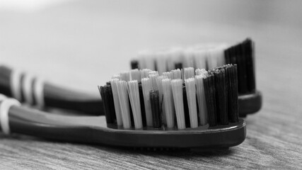 Two toothbrushes on a wooden background. Black and white image.