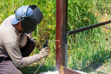A worker welds metal for a fence.