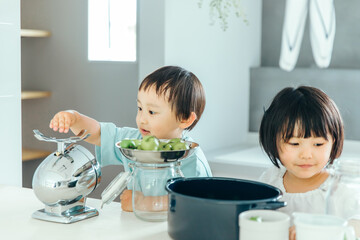 男の子と女の子兄弟が家のキッチンで料理のお手伝いをしている