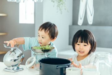 男の子と女の子兄弟が家のキッチンで料理のお手伝いをしている