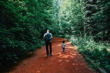 Obraz premium Father wearing a backpack and son holding a cane hiking together on a path in the forest, Istanbul, Turkey