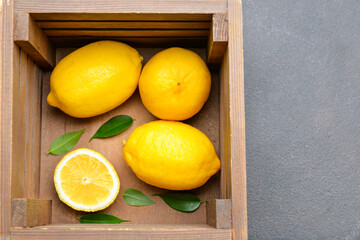 Wooden box with lemons on grey background