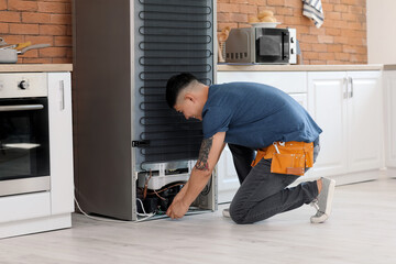 Worker repairing fridge in kitchen