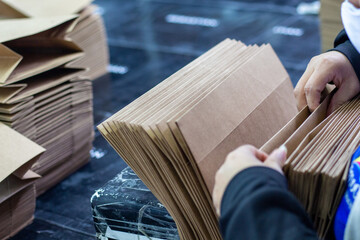 Pila de bolsas de papel siendo revisadas por trabajador en una fábrica de imprenta