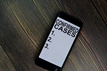 Confirmed Cases write on Smartphone. Supported by an additional services isolated on office desk.