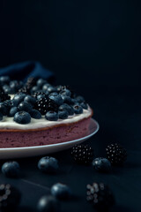 Cottage cheese casserole decorated with blackberry and blueberry on dark textured table.