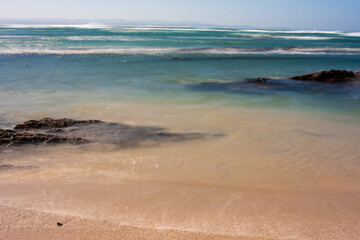 Fototapeta na wymiar Waves rolling into coastline with rocks protruding from water