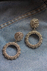 silver massive earrings on the background of blue jeans