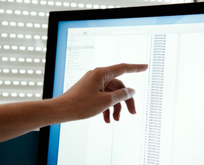 An index finger pointing at monitor.