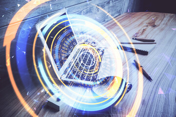 Computer on desktop in office with technology theme hologram. Double exposure. Tech concept.