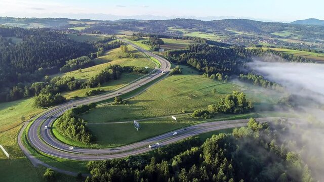 Poland. Winding switchback road from Krakow to Zakopane, called Zakopianka, near Rabka and Chabowka. Aerial video in sunrise light with morning fog. Far view of Tatra mountains in the background