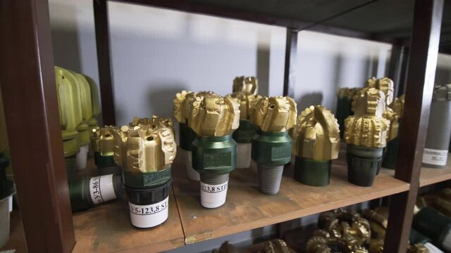 Golden color rock Drill Bits on shelving in stock. Oil drilling equipment for drilling rig operation on oil platform in oil and gas industry. Brand new PDC Polycrystalline Diamond Compact drilling bit