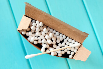 Cotton buds in a cardboard box. Wooden ear stick lies on top