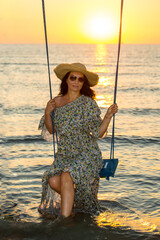 Beauty calm woman in the swing at sunrise