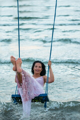 Woman swings over sea in the morning
