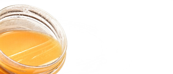 Glass jar with amber coloured honey, closeup detail, isolated on white background, space for text right side