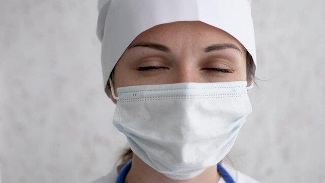 Portrait of a female doctor or nurse wearing medical cap and face mask looking at the camera. Ready to receive patients in hospital. Health care, medical concept. slow motion