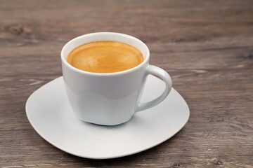 A white cup with coffee on a wooden background