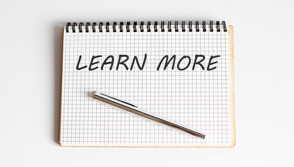 Handwriting text LEARN MORE on the notepad on white background