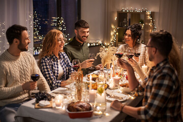 holidays, celebration and people concept - happy friends having christmas dinner at home drinking non-alcoholic red wine