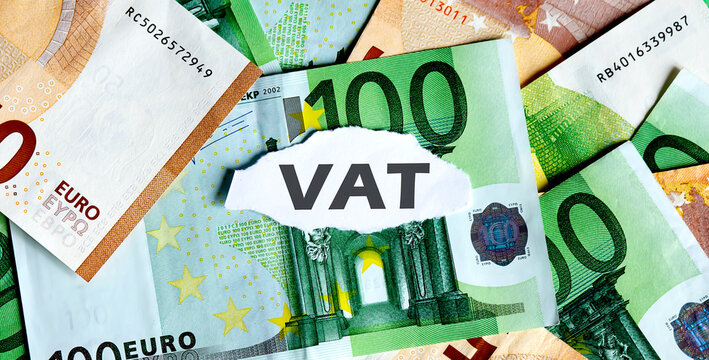 Focus on the word VAT, on piece of torn white paper with EUROS currency as a background.
