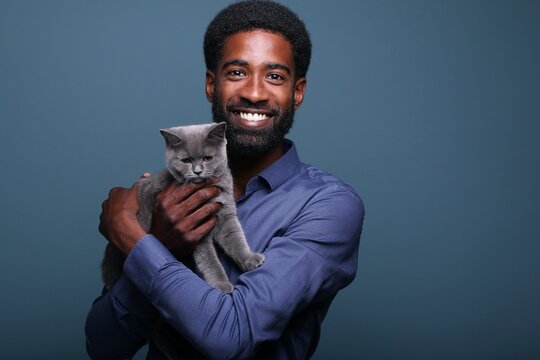 Beautiful afro man with a cat in front of a background
