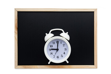 White alarm clock on the background of a black school board. The concept of the beginning of the school year.