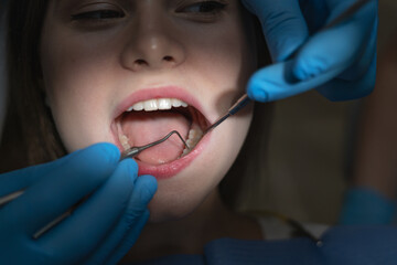 close-up of an open female mouth in bright light in a dark dentist office.
