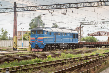 Fototapeta na wymiar Blue shunting locomotive rides through industrial area.