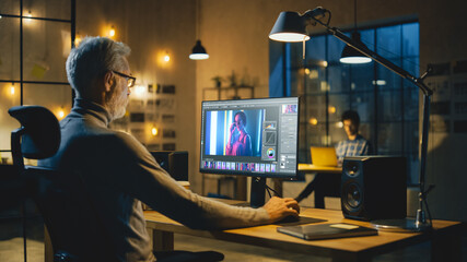 In the Late Evening Creative Middle Aged Photo Editor Works on a Desktop Computer Uses Image...