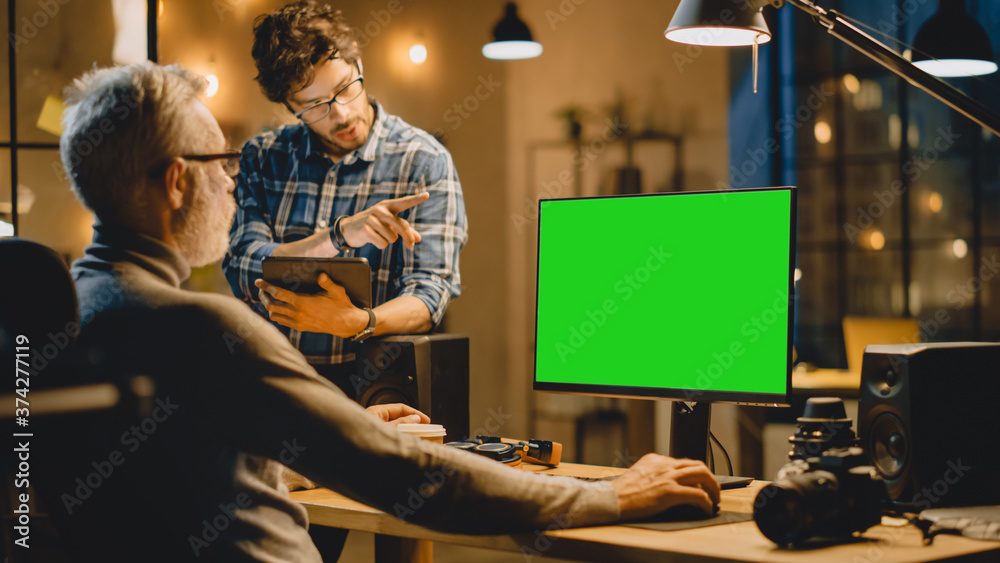 Poster in the evening creative middle aged man works on a desktop computer green mock-up screen, has conver