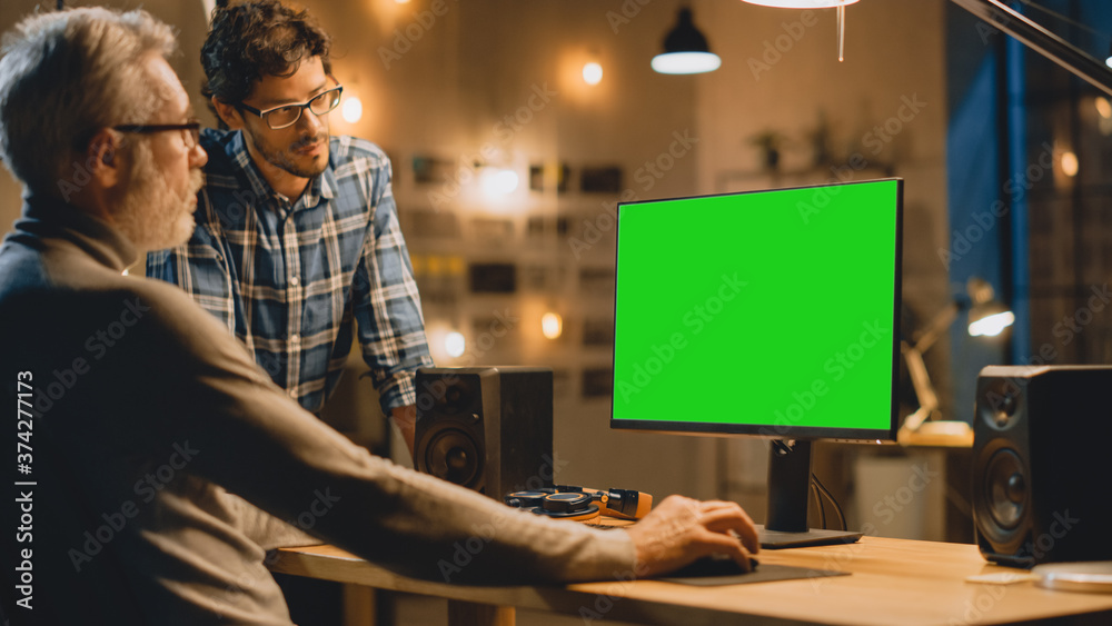 Poster in the evening creative middle aged man works on a desktop computer green mock-up screen, has conver