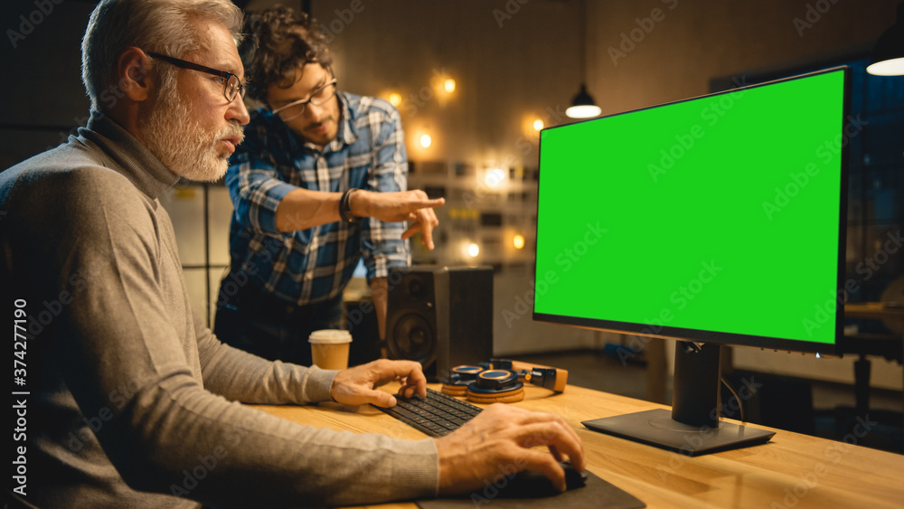 Poster in the evening creative middle aged man works on a desktop computer green mock-up screen, has conver