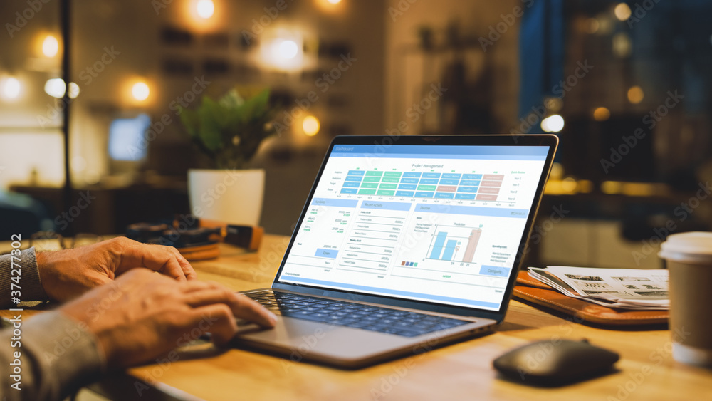 Poster close-up on the hands of the male specialist works on a laptop computer, screen shows various data a