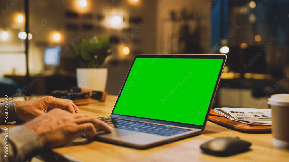 Poster close-up on the hands of the male specialist works on a laptop computer with mock-up green screen. i