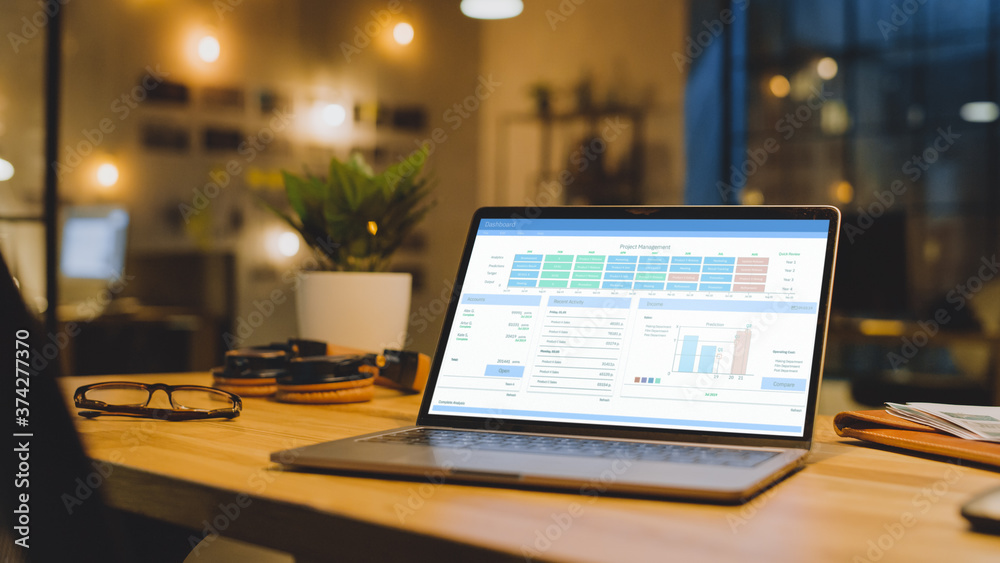 Poster laptop on the desk in the office shows company growth data with graphs, charts, software ui. in the 