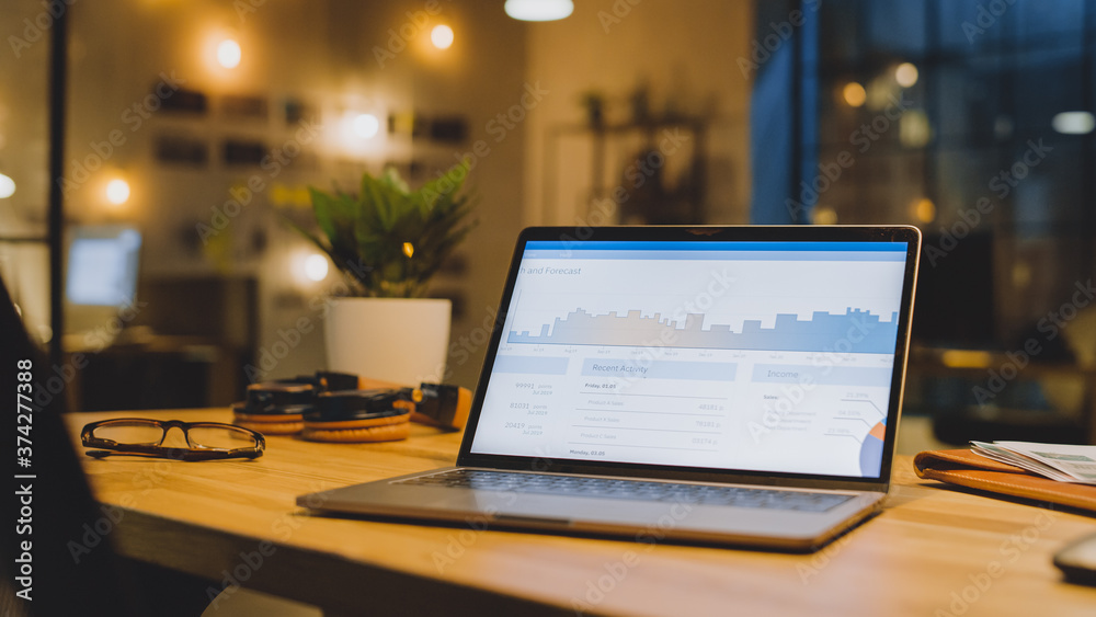 Poster laptop on the desk in the office shows company growth data with graphs, charts, software ui. in the 