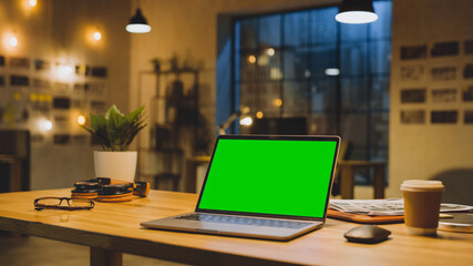 Mock-up Green Screen Stanting on the Desktop. In the Background Stylish Modern Office Studio in the Evening with Big Cityscape Window