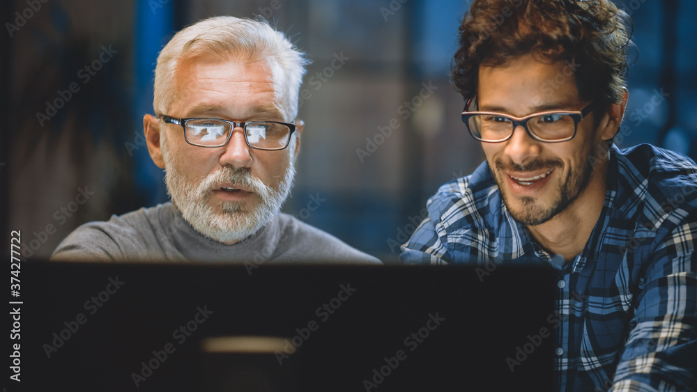 Poster chief creative designer shows desktop computer screen to a young developer, they discuss project. tw