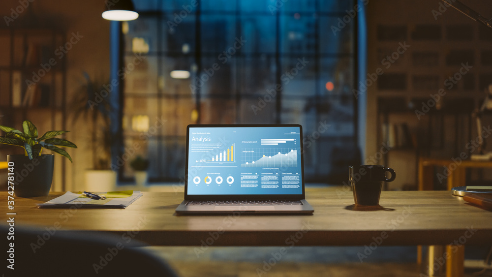 Poster Shot of a Laptop on a Desk with Statistics Graph, Chart and Various Data, Showing Company Growth and Success. In the Background Warm Evening Lighting and Open Space Studio with City Window View.