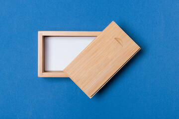 open wooden box with place for you logo on blue colored paper background. close up