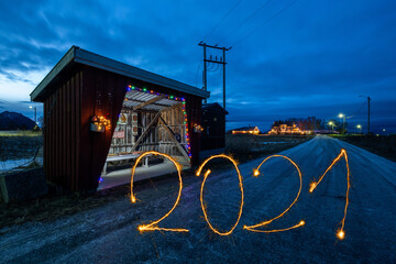 weihnachtlich geschmücktes Wartehäuschen in kalter Landschaft mit Jahreszahlen 2021, geschrieben...