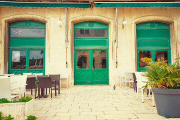 Fototapeta premium Sidewalk cafe near ancient bulding with green wooden windows.