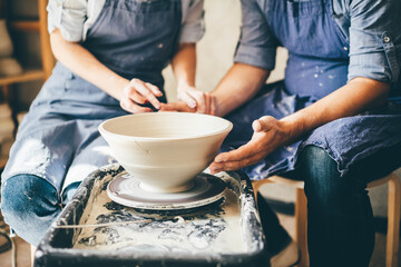 Fototapeta na wymiar Couple in love working together on potter wheel in craft studio workshop.
