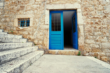 Stone old building with blue wooden vintage door and windows.