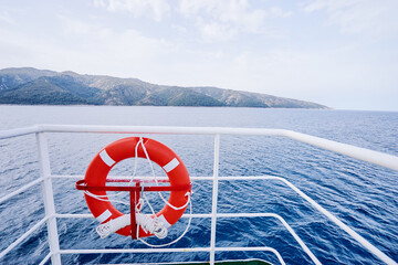 Red Lifebuoy in front of the blue sea on the ship.