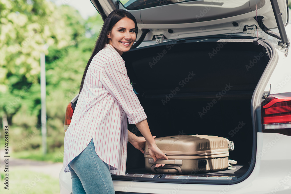 Poster photo of positive girl have summer time vacation put suitcase car trunk ready travel airport air fli