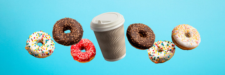 Donuts flying in the air and coffee paper cup on a blue background. Bakery, baking concept....